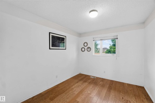 Wood-finish flooring with white baseboards, a white ceiling, and a flush mount light fixture - #28 3645 145 Av Nw, Edmonton, AB - Indoor Photo Showing Other Room
