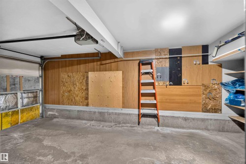Concrete flooring, wood paneling, overhead lighting, garage door, built-in shelving - #28 3645 145 Av Nw, Edmonton, AB - Indoor