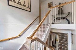 Multi-level staircase featuring a wood-finish handrail, white balusters, and carpeted treads - 