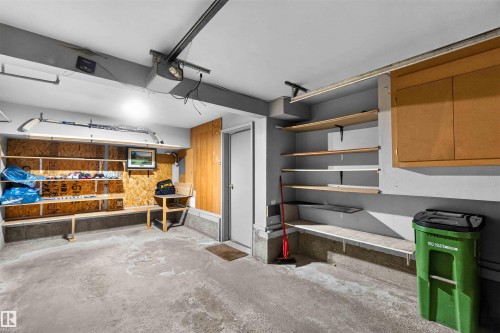Concrete flooring with a white door, built-in shelving, and overhead cabinetry - #28 3645 145 Av Nw, Edmonton, AB - Indoor Photo Showing Garage