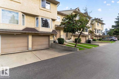 Stucco exterior with multiple bay windows, two-car garage, concrete driveway, and established landscaping - #28 3645 145 Av Nw, Edmonton, AB - Outdoor With Facade