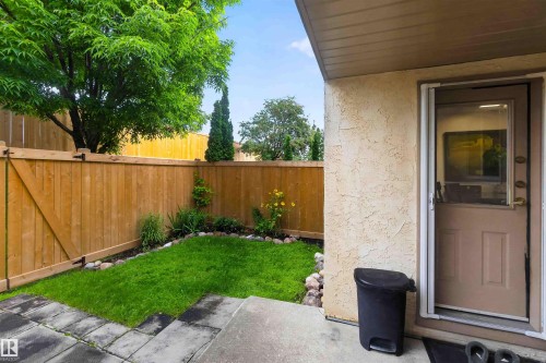 Private outdoor space featuring a wood fence, established lawn, and garden beds - #28 3645 145 Av Nw, Edmonton, AB - Outdoor