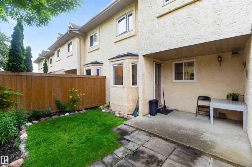 Rear exterior with stucco finish, a private concrete patio, and a fenced yard with a manicured lawn - #28 3645 145 Av Nw, Edmonton, AB - Outdoor With Exterior