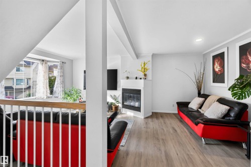 Living space featuring a built-in fireplace, recessed lighting, and wood-finish flooring - #28 3645 145 Av Nw, Edmonton, AB - Indoor With Fireplace