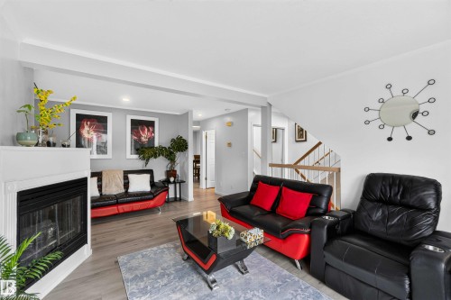 Recessed lighting, wood-finish flooring, white painted mantel with a fireplace insert, and a staircase with wood handrails - #28 3645 145 Av Nw, Edmonton, AB - Indoor Photo Showing Living Room With Fireplace