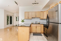 Kitchen featuring wood cabinetry, stainless steel appliances, and a dark stone countertop island - 