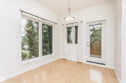 Wood-finish flooring, white walls, multiple windows, glass-paneled door, and a suspended ceiling light fixture - 