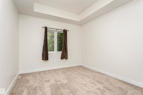 Recessed ceiling detail, neutral-toned carpeting, white walls, and a window for natural light - #219 10333 112 St Nw, Edmonton, AB - Indoor Photo Showing Other Room