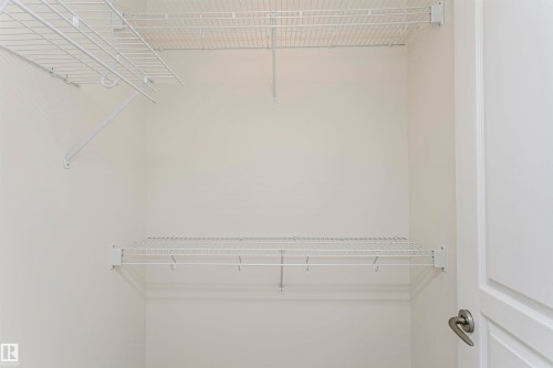Built-in wire shelving system with hanging rods and white walls - #219 10333 112 St Nw, Edmonton, AB - Indoor With Storage