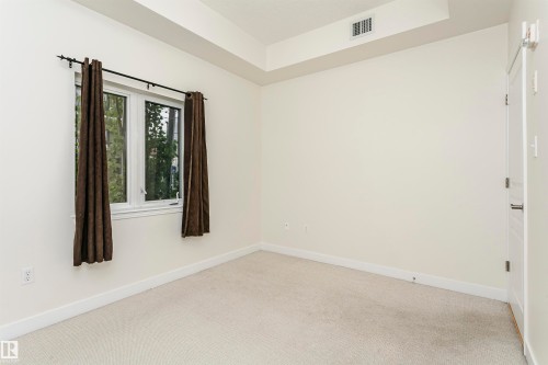 Neutral tone wall finish, white trim, recessed lighting, white panel door, and light-colored carpeting - #219 10333 112 St Nw, Edmonton, AB - Indoor Photo Showing Other Room