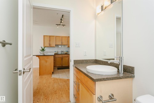 Bathroom vanity with an oval vessel sink, chrome faucet, and speckled countertop - #219 10333 112 St Nw, Edmonton, AB - Indoor Photo Showing Bathroom