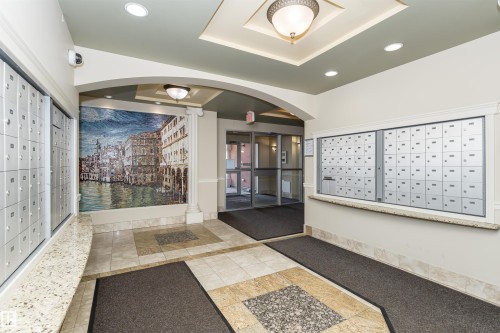 Recessed lighting, decorative ceiling fixture, tiled flooring, built-in mailboxes, glass entry doors - #219 10333 112 St Nw, Edmonton, AB - Indoor Photo Showing Other Room