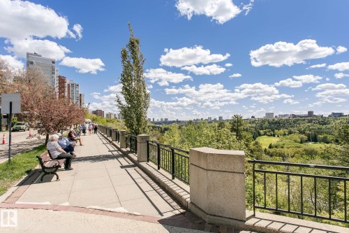 Paved promenade with metal railings, bordered by established trees and high-rise structures - #219 10333 112 St Nw, Edmonton, AB - Outdoor With View