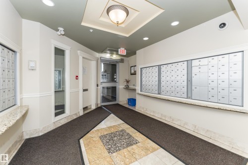 Building entrance featuring a glass door, built-in mailboxes, granite-look countertops, and a decorative ceiling fixture - #219 10333 112 St Nw, Edmonton, AB - Indoor Photo Showing Other Room