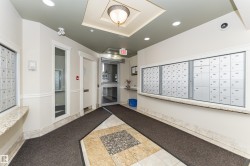 Building entrance featuring a glass door, built-in mailboxes, granite-look countertops, and a decorative ceiling fixture - 