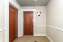 Entryway with wood-finish doors, detailed white trim, and a decorative wall sconce - #219 10333 112 St Nw, Edmonton, AB  - Indoor Photo Showing Other Room 