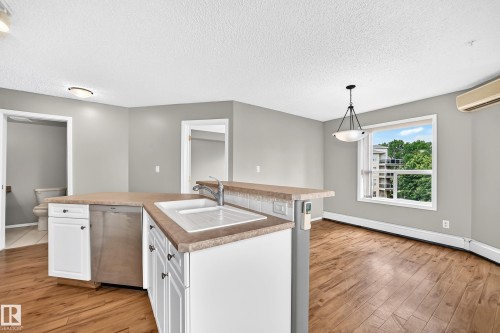 Kitchen island with integrated sink and stainless steel dishwasher - #331 9704 174 St Nw, Edmonton, AB 