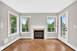 Wood-finish flooring with a white trim fireplace and three distinct windows - 