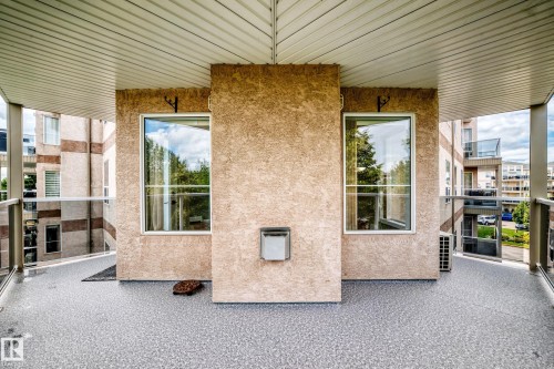 Outdoor balcony with a textured floor finish, glass and metal railings, and a slatted ceiling - #331 9704 174 St Nw, Edmonton, AB 