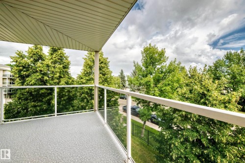 Balcony featuring a textured floor, glass railing, and a slatted ceiling - #331 9704 174 St Nw, Edmonton, AB 