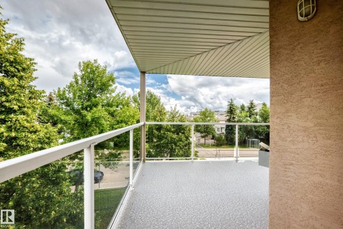 Balcony featuring a textured floor surface, clear panel railings, and a slatted ceiling overhead - #331 9704 174 St Nw, Edmonton, AB 