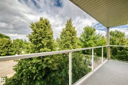 Balcony with glass panel railing, textured flooring, and a slat-paneled ceiling - 