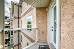 Balcony with glass railing, textured exterior finish, and a white framed door - 