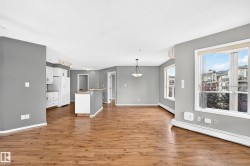 Wood-finish flooring throughout, white kitchen cabinetry with contemporary hardware, and a center island - 