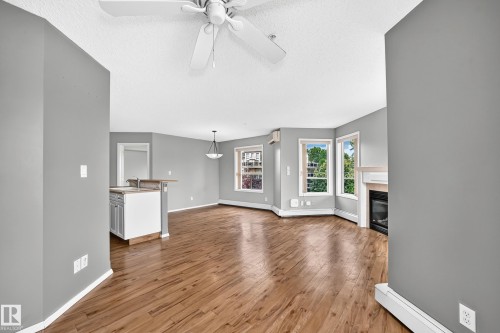 Wood-finish flooring, ceiling fan, built-in fireplace, multiple windows, and a breakfast bar with cabinetry - #331 9704 174 St Nw, Edmonton, AB 