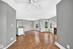 Wood-finish flooring, ceiling fan, built-in fireplace, multiple windows, and a breakfast bar with cabinetry - 