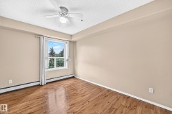 Wood-finish flooring, neutral-toned walls, a window with exterior scenery, a ceiling fan with integrated lighting, and white trim - 
