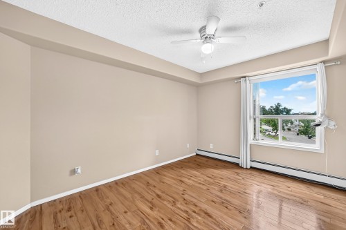 Wood-finish flooring, neutral wall paint, and a white ceiling fan with integrated lighting - #331 9704 174 St Nw, Edmonton, AB 