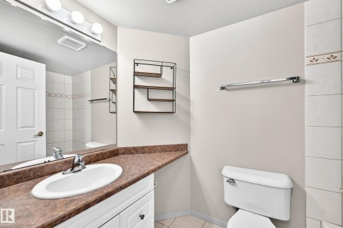 White vanity with a brown countertop, undermount sink, and chrome faucet - #331 9704 174 St Nw, Edmonton, AB 
