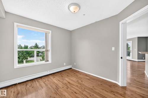 Wood-finish flooring, neutral wall tones, and a bright window with white trim - #331 9704 174 St Nw, Edmonton, AB 