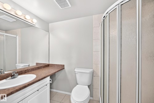 Bathroom featuring a white vanity with an integrated sink, brown countertop, and a vanity mirror with overhead lighting - #331 9704 174 St Nw, Edmonton, AB 