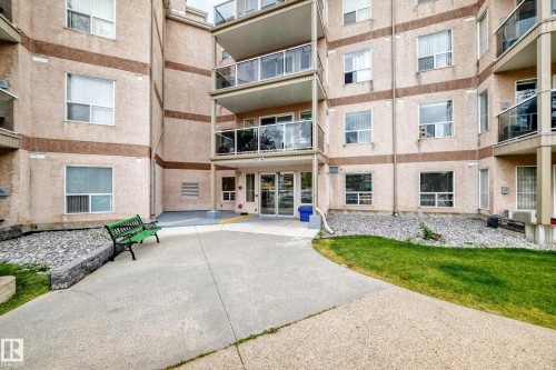Multi-story building exterior with textured light-colored stucco and brown accent banding - #331 9704 174 St Nw, Edmonton, AB 