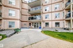 Multi-story building exterior with textured light-colored stucco and brown accent banding - 