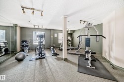 Fitness area with wall-to-wall carpeting, track lighting, and mirrored wall - 