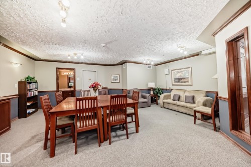 Open-concept gathering space with carpeted flooring, two-tone wall treatment, and crown molding - #331 9704 174 St Nw, Edmonton, AB 