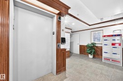 Elevator access within a tiled corridor featuring wood trim and recessed lighting - 