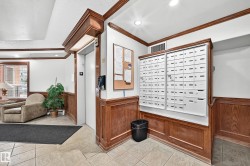 Lobby area featuring wood-paneled walls, a built-in mailbox system, and a passenger elevator - 