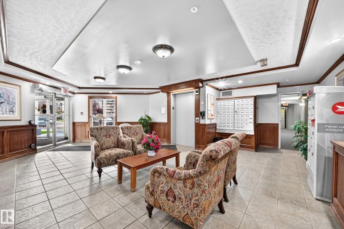 Lobby featuring tile flooring, wood paneling, decorative ceiling trim, and overhead lighting - #331 9704 174 St Nw, Edmonton, AB 