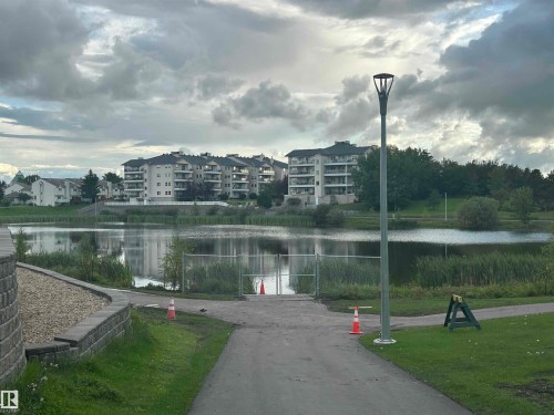 Waterfront property featuring apartment buildings, a paved pathway, and a modern street light - #331 9704 174 St Nw, Edmonton, AB 