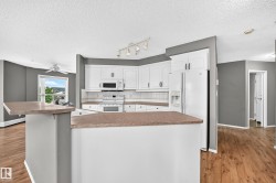 Kitchen featuring white cabinetry, white appliances, a tile backsplash, and a breakfast bar - 
