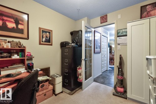Carpeted room with a built-in white storage cabinet and an adjacent doorway featuring French doors - #210 7909 71 St Nw, Edmonton, AB - Indoor