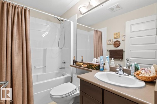 Bathroom featuring a vanity with an integrated sink, a built-in bathtub with a shower, and a large wall-mounted mirror - #210 7909 71 St Nw, Edmonton, AB - Indoor Photo Showing Bathroom
