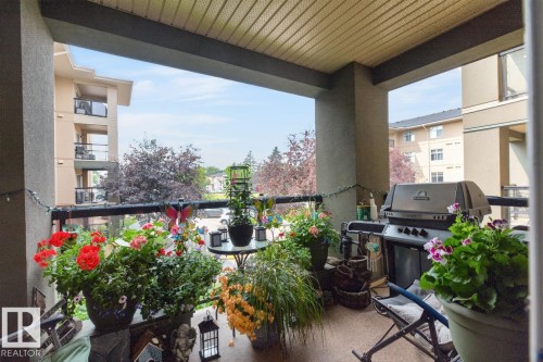 Covered balcony featuring a textured ceiling, a metal railing, and an outdoor light string - #210 7909 71 St Nw, Edmonton, AB - Outdoor With Balcony With Exterior