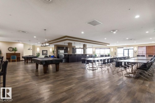 Spacious common area featuring wood-finish flooring, recessed lighting, and large windows - #210 7909 71 St Nw, Edmonton, AB - Indoor