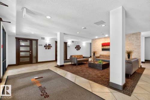 Tiled flooring, recessed lighting, and a textured accent wall define this common area - #210 7909 71 St Nw, Edmonton, AB - Indoor Photo Showing Other Room
