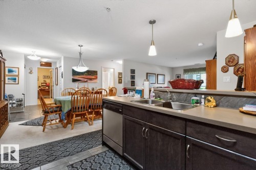 Kitchen featuring stainless steel appliances, dual basin sink, and pendant lighting - #210 7909 71 St Nw, Edmonton, AB - Indoor Photo Showing Other Room